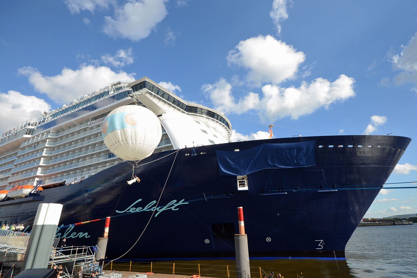 Taufe von "Mein Schiff 3": Noch ist der Schriftzug am Bug von dunkelblauem Tuch verdeckt: Während der Taufzeremonie hängt Schlagerstar Helene Fischer für einen Moment am Trapez eines Ballons. Noch ist der Schriftzug am Bug von dunkelblauem Tuch verdeckt: Während der Taufzeremonie hängt Schlagerstar Helene Fischer für einen Moment am Trapez eines Ballons.
