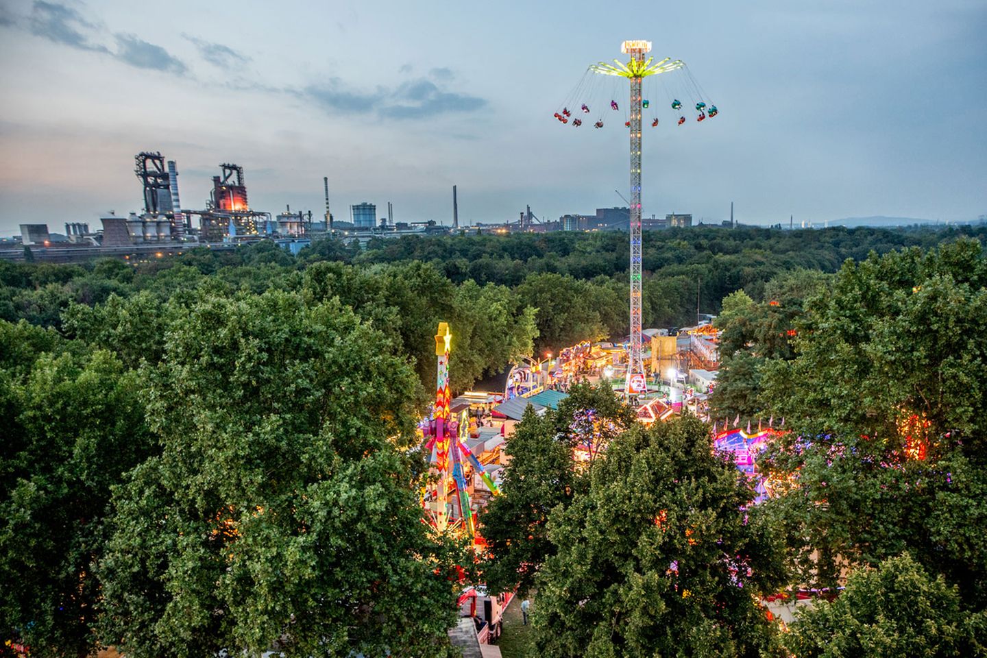 Die Beecker Kirmes ist eine der größten Ereignisse zwischen Niederrhein und Ruhrgebiet. Im Hintergrund sind die stillgelegten Hochöfen von Thyssen zu sehen.