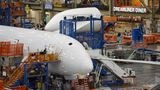 Noch sind die Cockpitscheiben hinter weißer Kunststofffolie verborgen: Nicht aus glänzenden Aluminium wird der Rumpf zusammengenietet, sondern aus vorgefertigten Baugruppen. Im Hintergrund ist eine Kantine für die Boeing-Mitarbeiter zu sehen: der Dreamliner Diner.