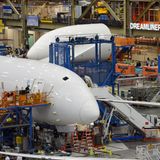 Noch sind die Cockpitscheiben hinter weißer Kunststofffolie verborgen: Nicht aus glänzenden Aluminium wird der Rumpf zusammengenietet, sondern aus vorgefertigten Baugruppen. Im Hintergrund ist eine Kantine für die Boeing-Mitarbeiter zu sehen: der Dreamliner Diner.