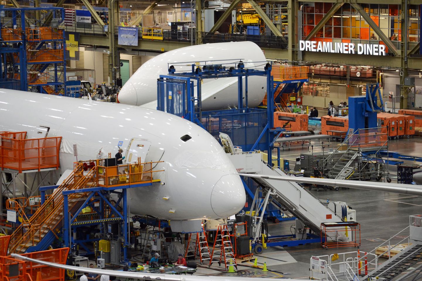 Noch sind die Cockpitscheiben hinter weißer Kunststofffolie verborgen: Nicht aus glänzenden Aluminium wird der Rumpf zusammengenietet, sondern aus vorgefertigten Baugruppen. Im Hintergrund ist eine Kantine für die Boeing-Mitarbeiter zu sehen: der Dreamliner Diner.