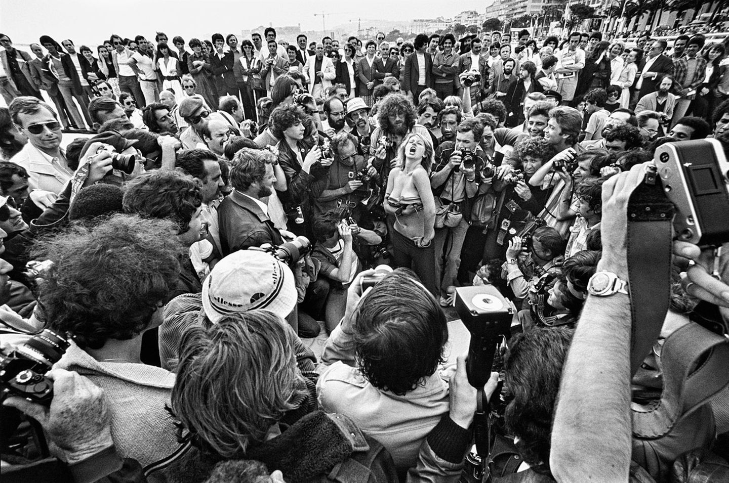 1980 besuchte der Fotofgraf das Filmfestival in Cannes. Dabei entstand diese Aufnahme einer knapp bekleideten Frau, die von zumeist fotografierenden Männern umringt ist.