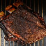 Heizen Sie ihren Smoker auf 100 bis maximal 120 Grad ein. Gerade die zähe Rinderbrust wird zarter, wenn bei niedriger Temperatur und dafür länger gegart wird.    Legen Sie die Rinderbrust mit der Fettseite nach oben auf den Grillrost! Das Fett schmilzt während des Smokens und soll am Fleisch herunterlaufen und ihm so zusätzlich Feuchtigkeit und Würze geben.    Jetzt noch das Fleischthermometer tief ins Fleisch stechen, den Deckel schließen und warten. Alle 90 Minuten das Fleisch mit dem Mop bestreichen. Das Brisket ist fertig, wenn in seinem Kern gut 90 Grad erreicht sind.    Nehmen Sie das gute Stück aus dem Smoker und wickeln es fest in zwei, drei Lagen Alufolie. Geben Sie ihrem Brisket nun noch 20 Minuten Zeit zum Entspannen. Schneiden Sie anschließend die Fettschicht herunter. Fertig! Tipp: Brisket wird dünn gegen die Faser geschnitten.