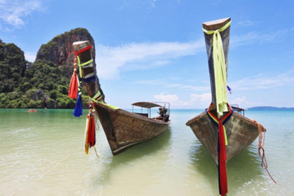 Farbenfroh verzierte Longtail-Boote liegen am Strand von Phuket