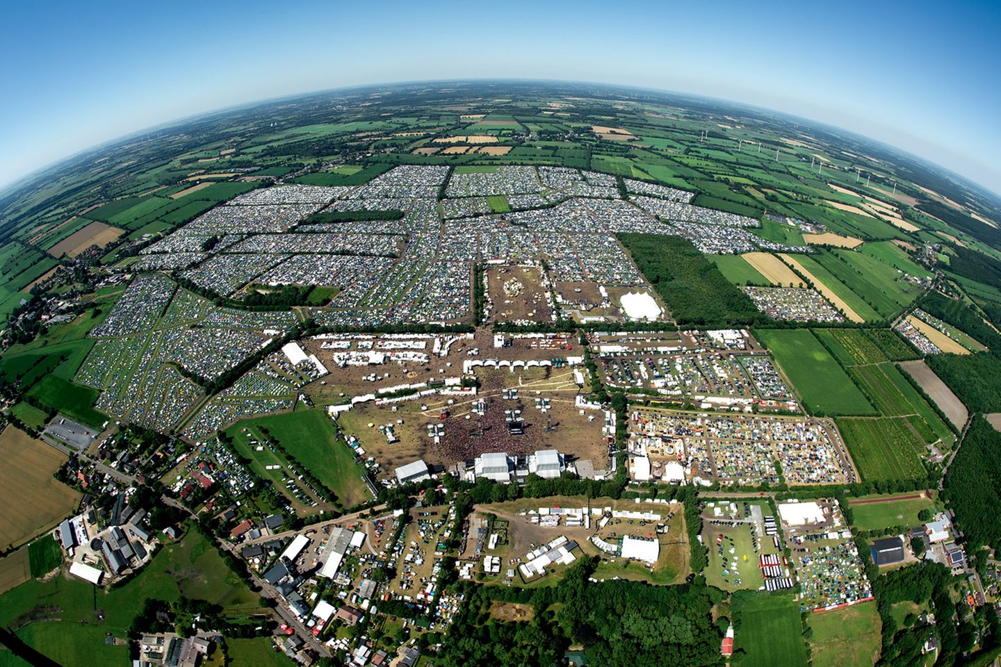 Das Festival-Gelände und der Campground aus der Luft. Die Äcker sind übersät mit Zeltplätzen, Wagenburgen, Imbissbuden und zahlreichen Bühnen; die Wege zwischen den Campground-Arealen sind benannt nach berühmten Bands ("AC/DC Street", "Nightwish Boulevard", "Metallica Avenue").