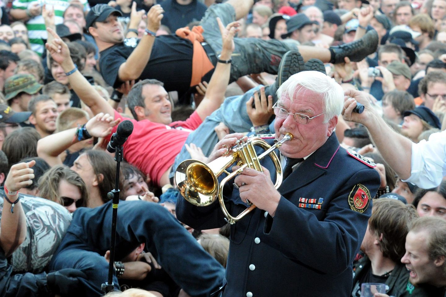 25 Jahre Matsch und Metal: Trompete statt Gitarrenriffs: Die Wacken Firefighters, die Blaskapelle der örtlichen Feuerwehr, spielen zum Festival-Auftakt im Biergarten Volkslieder und Adaptionen bekannter Songs. Im Hintergrund verwandelt sich die tobsüchtige Meute in ein betrunkenes, schunkelndes Menschenmeer. Trompete statt Gitarrenriffs: Die Wacken Firefighters, die Blaskapelle der örtlichen Feuerwehr, spielen zum Festival-Auftakt im Biergarten Volkslieder und Adaptionen bekannter Songs. Im Hintergrund verwandelt sich die tobsüchtige Meute in ein betrunkenes, schunkelndes Menschenmeer.