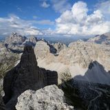 Kleine Zinne: Südkante  Blick vom Vorgipfel der Kleinen Zinne auf das nordöstliche Ende der Dolomiten mit Dreischusterspitze und Paternkofel. Dazwischen schmiegt sich auf dem Pass die Drei-Zinnen-Hütte. Rechts im Schatten verläuft der Fußweg vom Parkplatz an der Auronzo-Hütte über den Paternsattel zur Drei-Zinnen-Hütte. In den Sommermonaten laufen über diese "Drei-Zinnen-Autobahn" die Touristenmassen, um einen Blick auf die berühmten Nordwände zu erhaschen.