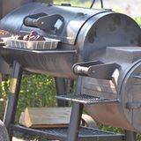 Ein handelsüblicher Edel-Smoker für den Garten. Das Feuer brennt durch die weit geöffnete Luftzufuhr ordentlich in der Feuerbox