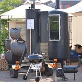 Die Ausrüstung des deutschen Grillteams "Feuer und Eisen" bei der Grillweltmeisterschaft in Gronau im Juni 2011. Es ist alles dabei: Ganz rechts ein Mini-Smoker, gefolgt von einem Kugeglrill, einem großen auf einem Hänger montierten Smoker und einer mächtigen Räucherkammer
