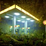 Von David LaChapelle inszeniert und illuminiert sieht diese Shell-Tankstelle aus, als läge sie mitten im Urwald. Sie wirkt wie eine Kulisse in einem David-Lynch-Film