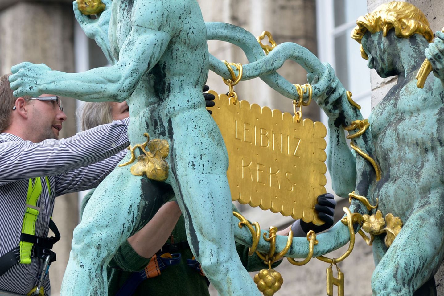Zwei Mechaniker hängen den goldenen Keks wieder dorthin, wo er hingehört - ans Bahlsen-Firmengebäude in Hannover.