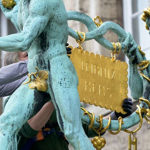 Zwei Mechaniker hängen den goldenen Keks wieder dorthin, wo er hingehört - ans Bahlsen-Firmengebäude in Hannover.