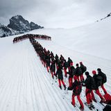 Formation in Pfeilform: Skifahrer beim Julierpass mit dem Piz Güglia im Kanton Graubünden im Hintergrund.