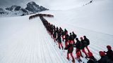 Formation in Pfeilform: Skifahrer beim Julierpass mit dem Piz Güglia im Kanton Graubünden im Hintergrund.