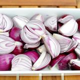 Ist die Schale unten, wird die Zwiebel geviertelt. Die Stücke kommen in eine Auflaufform.