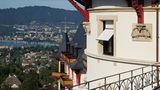Belle Epoche über den Dächern von Zürich: Zipfelmützenzwerge und beflügelte Dämonen tragen an der alten Schlossfassade Teile der hölzernen Dachkonstruktion