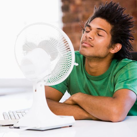 Hitze im Büro: Ein mann sitzt vor einem Ventilator