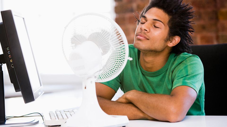 Hitze im Büro Hitze im Büro: Ein mann sitzt vor einem Ventilator