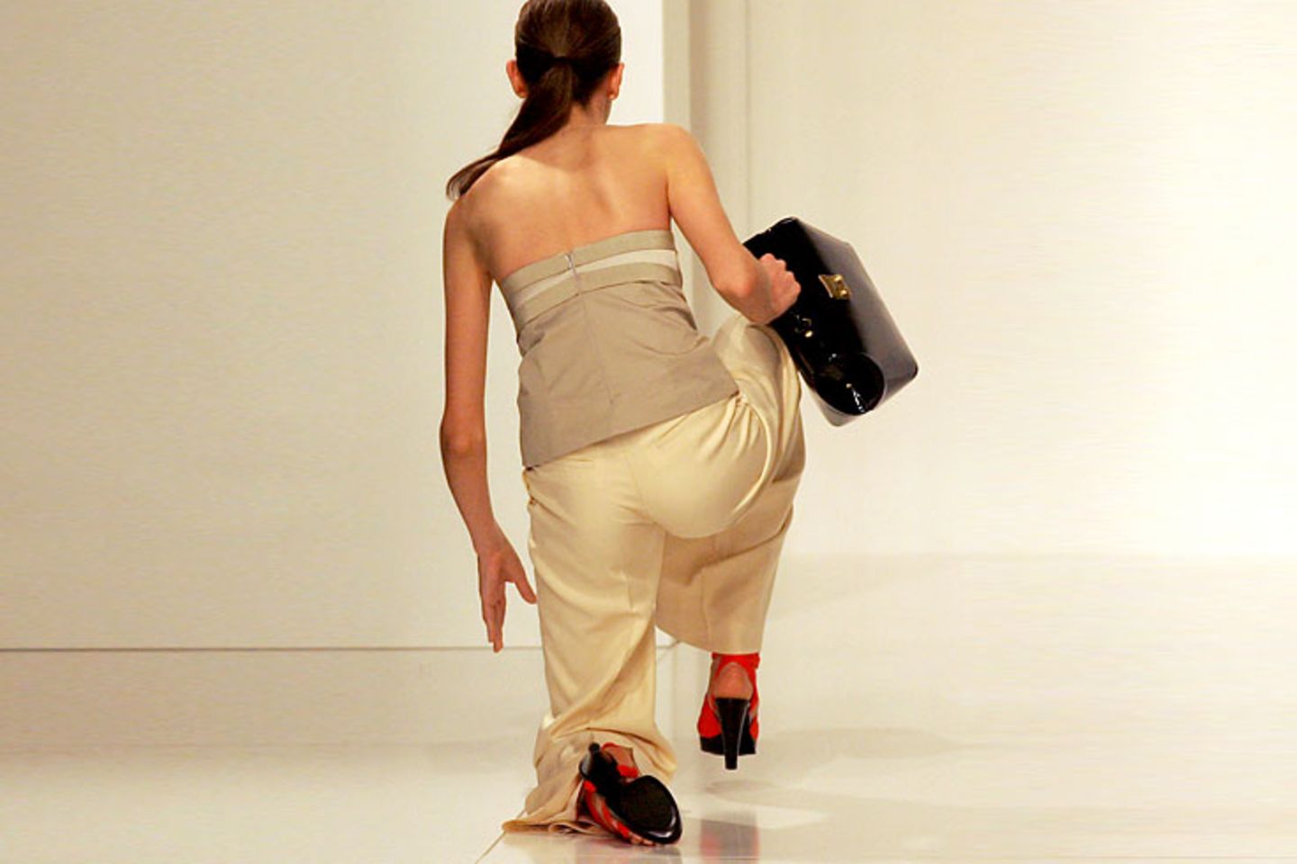 Hohe Absätze, weite Hosen und eine Tasche in der Hand machen das Aufstehen zum echten Balanceakt.