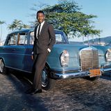 Brasilien, 1966, Abendsonne – der Fußballer Pelé steht im feinen Anzug stolz neben seinem neuen Mercedes- Benz Saloon