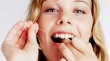 Mit Zahnseide und Zwischenraumbürsten lassen sich die Beläge zwischen den Zähnen entfernen
