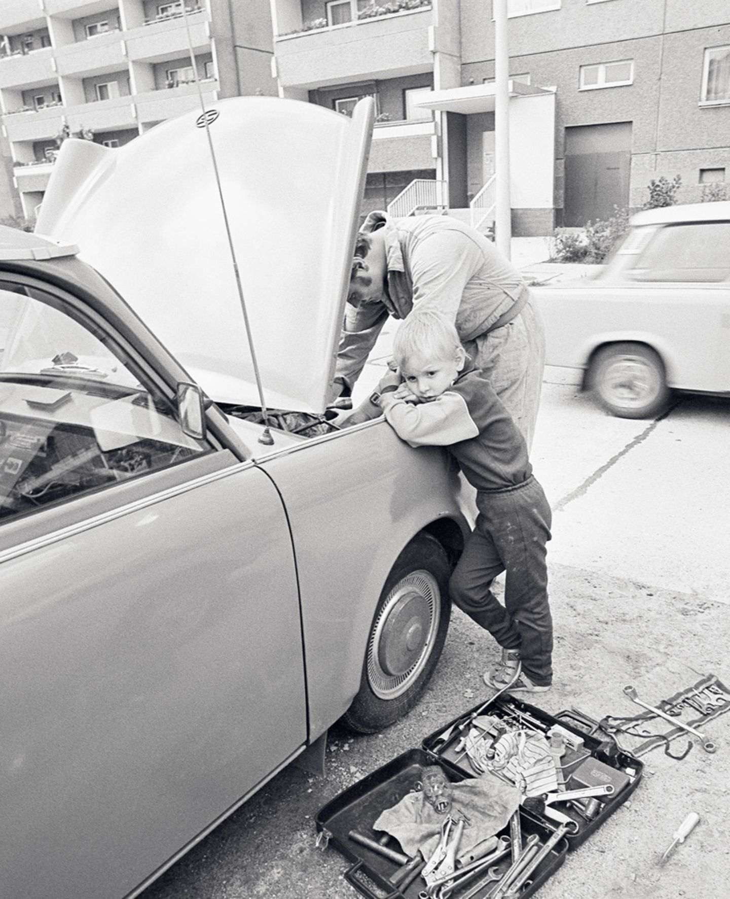 Und auch in diesem Punkt unterschieden sich deutsche Männer in Ost und West kaum: Papi schraubt gerne am Auto rum. Das Foto entstand 1987 in Berlin-Marzahn.
