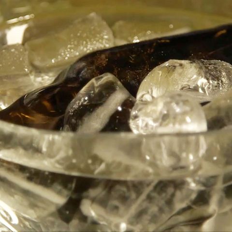 Eine Flasche Bier liegt in einer Schüssel mit Eiswürfeln.