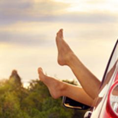 Nackte Füße werden aus dem offenen Fenster eines Autos gestreckt.