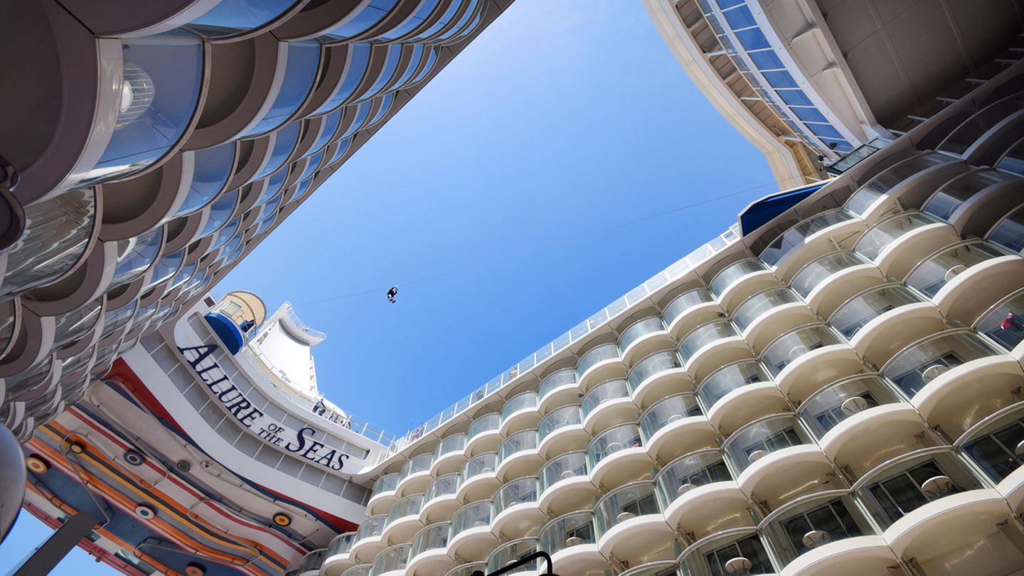 Die Perspektive des riesigen Patios im Heck auf Deck 6 zeigt die diagonale Seilrutsche mit einer über dem Abgrund schwebenden Person - eine der unendlichen vielen Freizeitmöglichkeiten von Kletterwänden bis zum Schlittschuhlaufen an Bord.