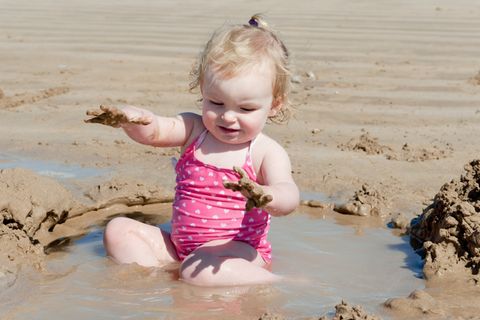 Ein Kind spielt im Sand - und zwar mit vollem Körpereinsatz