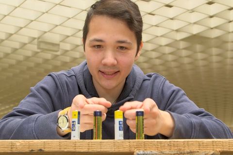 Vier Batterien stehen vor einem jungen Mann.