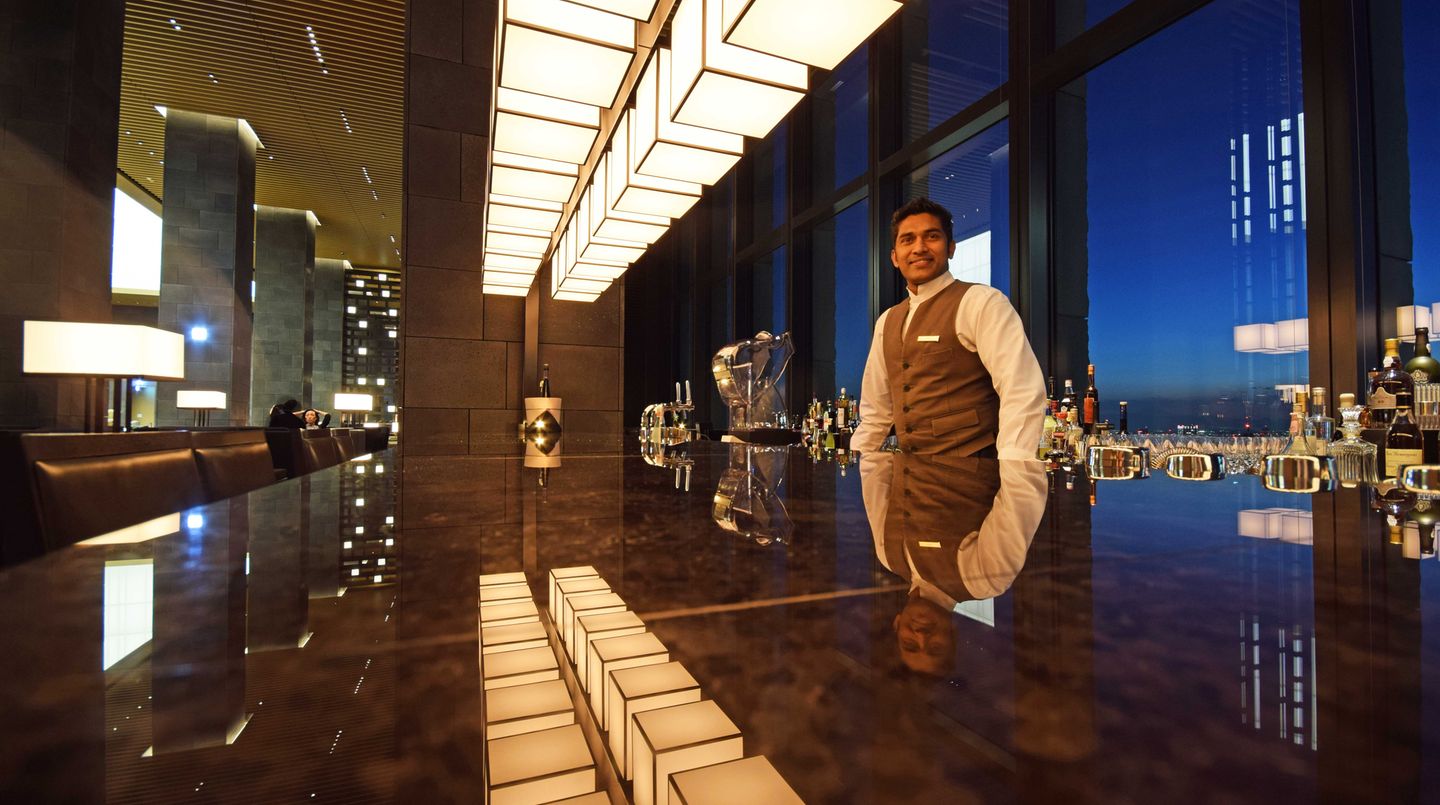 Im poliertem Marmortresen spiegelt sich die Bar, die sich wie das Restaurant hinter den Säulen der Lobby versteckt und durch die Ausrichtung nach Südwesten die Sonnenuntergänge einbezieht.