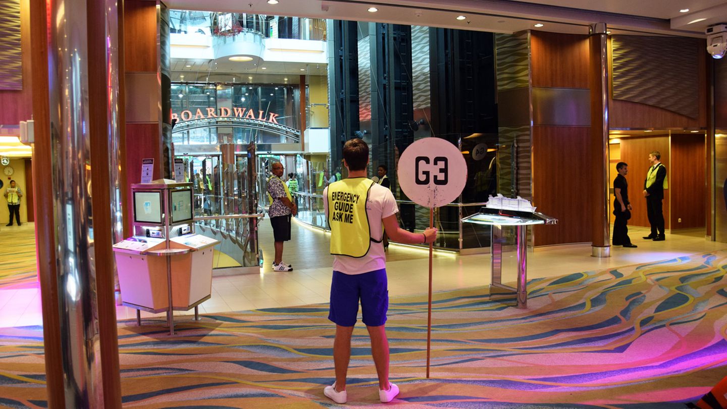 Auf Deck 5 und 6 ziehen sich Boardwalk und Royal Promenade mit Geschäften und Bars wie eine Shopping Mall durch das Längsschiff. Hier ein Bild von der Rettungsübung, die bereits vor dem Auslaufen des Schiffs absolviert wird. Auf meiner Chipkarte, die meine Kabinentür öffnet und gleichzeitig als Zahlungsmittel dient, ist zwar der Ort des Notfall-Sammelplatzes mit G3 größer markiert als die Kabinennummer. Allerdings bleibt mir die Seenotübung ein Rätsel. Während der halben Stunde des Rumstehens lerne ich viele Mitreisende kennen, doch wo sich meine Schwimmweste für den "unlikely event of an emergency" befindet, wird mir nicht verraten. Lautes Wassergeplätscher von einem Indoor-Springbrunnen übertönt die Durchsagen der Crew.