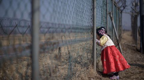 Südkoreanisches Mädchen blickt durch einen Grenzzaun