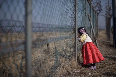 Südkoreanisches Mädchen blickt durch einen Grenzzaun