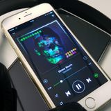 Ein iPhone mit geöffneter Musik-App liegt auf einem Android-Smartphone