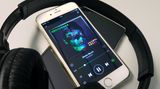 Ein iPhone mit geöffneter Musik-App liegt auf einem Android-Smartphone