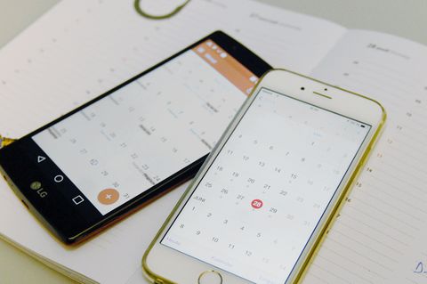 Ein iPhone und ein Android-Smartphone liegen mit geöffneter Kalender-App auf einem Papier-Planer