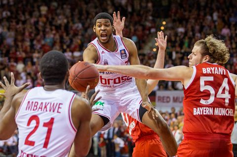 John Bryant (r.) von München im Kampf um den Ball mit den Bamberger Spielern Trevor Mbakwe (l.) und Ryan Thompson