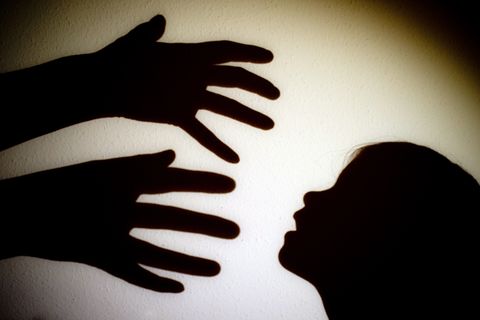 Schatten von Händen einer erwachsenen Person und dem Kopf eines Kindes an einer Wand eines Zimmers