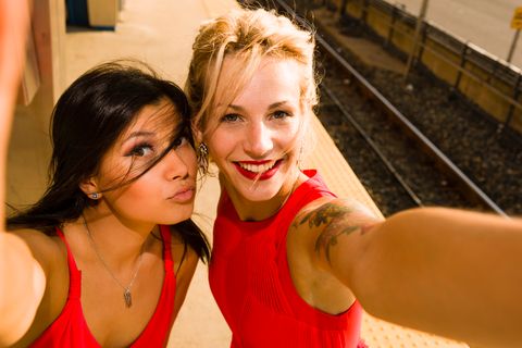 Zwei junge Frauen machen ein Selfie neben einem Bahngleis