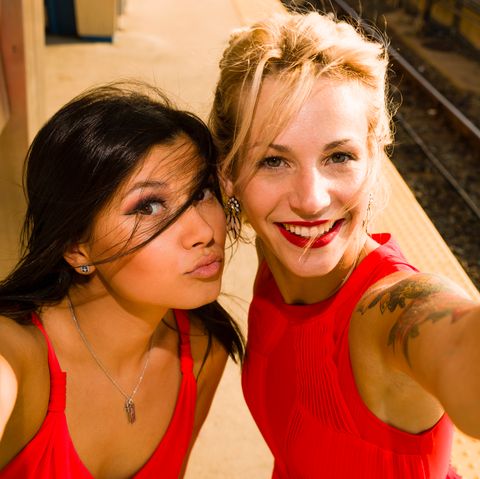 Zwei junge Frauen machen ein Selfie neben einem Bahngleis