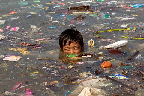 Ein Junge schwimmt in Manila in Wasser voller Müll