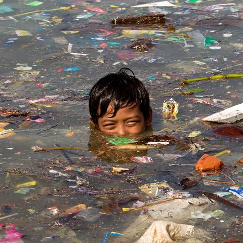 Ein Junge schwimmt in Manila in Wasser voller Müll