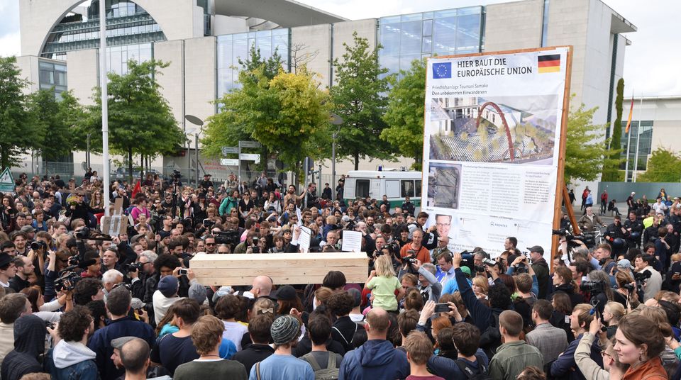 Die Toten Kommen Ein Holzsarg wird im Rahmen der Aktion "Marsch der Entschlossenen" vom Zentrums für Politische Schönheit vor das Kanzleramt getragen. Im Hintergrund steht ein symbolisches Bauschild mit der Aufschrift "Hier baut die Europäische Union - Friedhofsanlage - Den unbekannten Einwanderern"