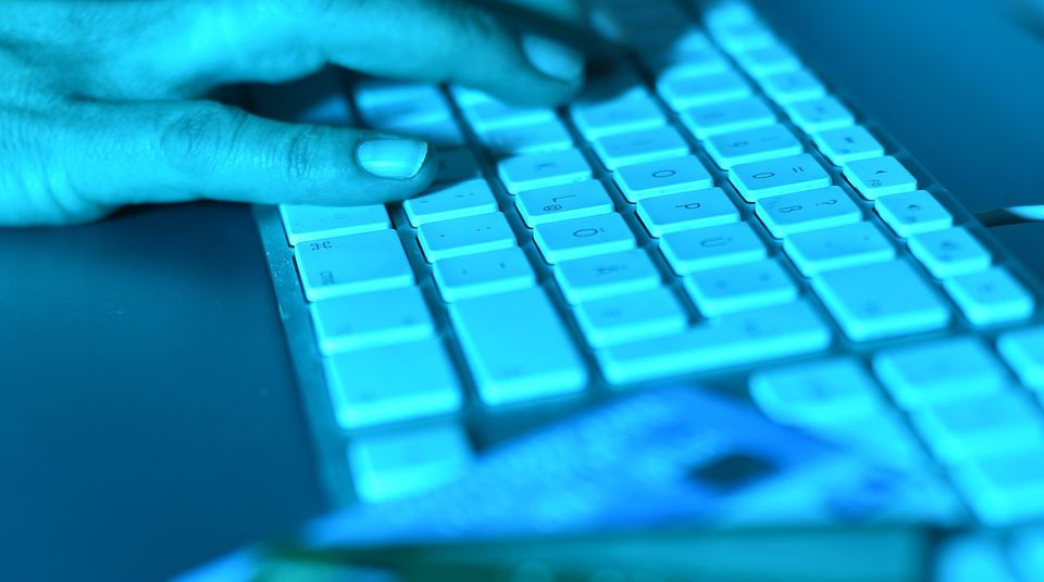 Die Abzocke bei Facebook durch Klon-Profile nimmt zu. Zu sehen ist eine Hand auf einer Tastatur, daneben Kredikarten
