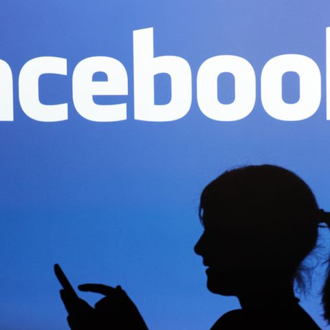 Vor dem Facebook-Logo ist der Schatten einer Frau zu sehen.