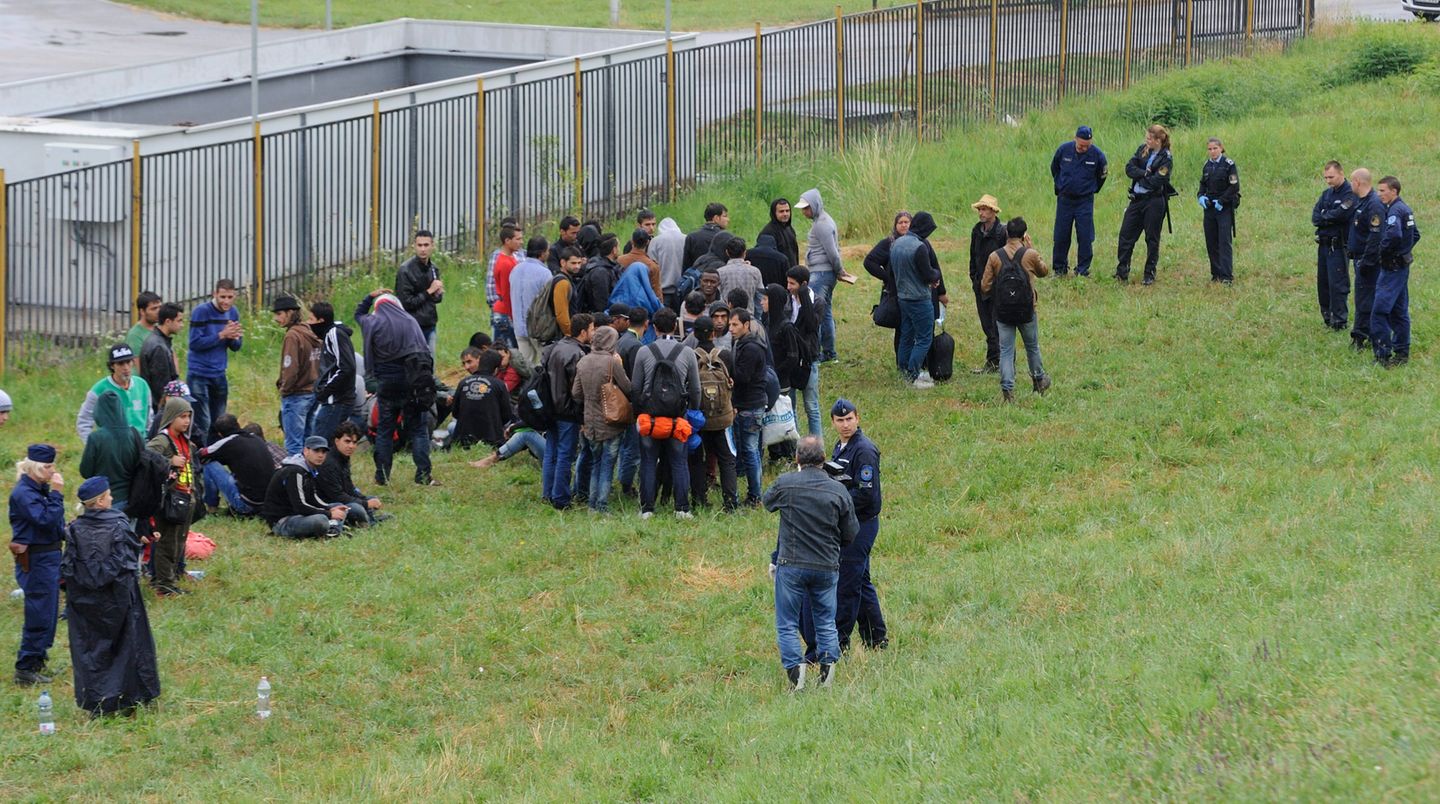 Ungarische Polizisten bewachen Flüchtlinge, die sie an der Grenze festgenommen haben