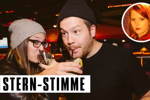 Zwei junge Menschen stehen in einer Bar und trinken Alkohol