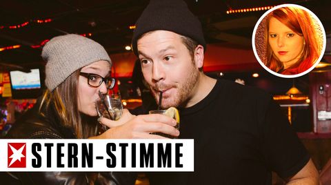 Zwei junge Menschen stehen in einer Bar und trinken Alkohol